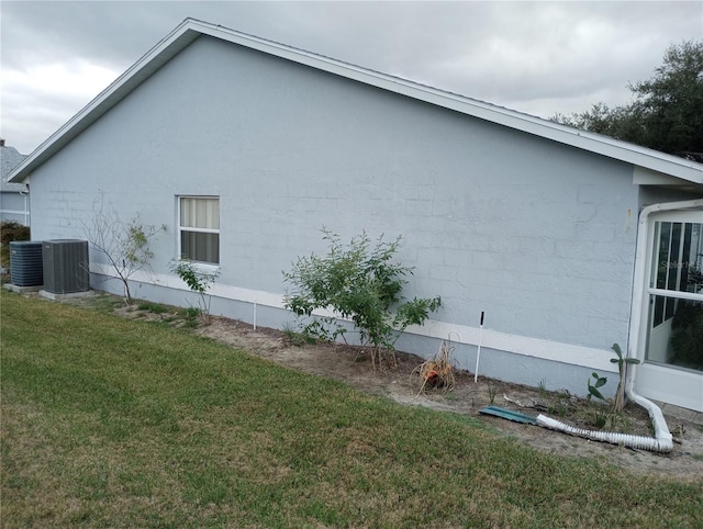 view of side of home featuring central AC and a lawn