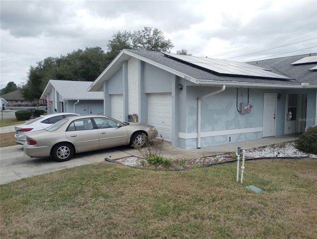 view of side of property featuring solar panels, a garage, and a lawn