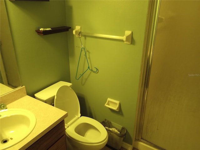 bathroom featuring vanity, a shower with shower door, and toilet