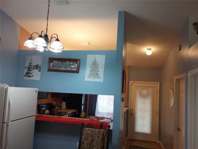 kitchen featuring black refrigerator, white refrigerator, decorative light fixtures, a chandelier, and range