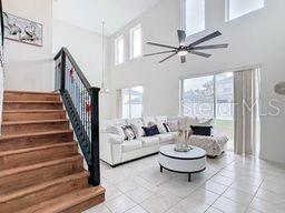 living room featuring ceiling fan, a towering ceiling, and light tile patterned floors