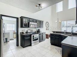 kitchen with appliances with stainless steel finishes, light tile patterned floors, ceiling fan, and sink