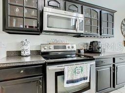 bar featuring dark brown cabinetry, light tile patterned floors, and appliances with stainless steel finishes