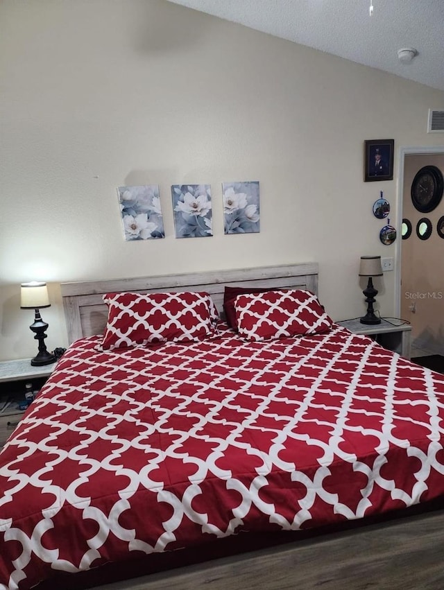 bedroom with wood-type flooring, a textured ceiling, and lofted ceiling