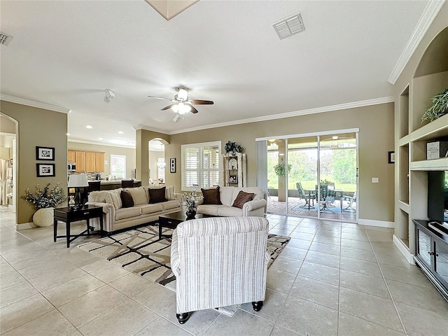 tiled living room featuring built in shelves, ceiling fan, and crown molding