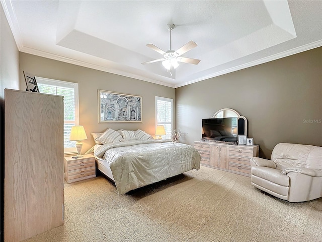 carpeted bedroom with a raised ceiling, ceiling fan, and crown molding