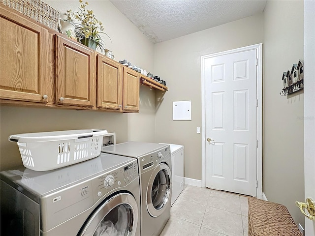 laundry area featuring cabinets, a textured ceiling, separate washer and dryer, and light tile patterned flooring