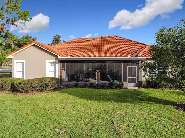 back of house featuring a lawn and a sunroom