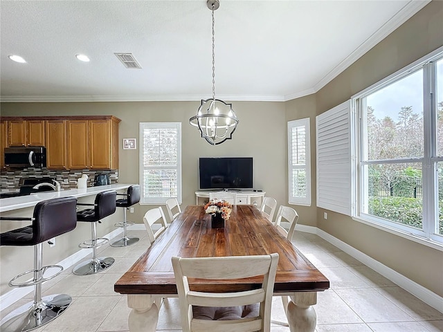 tiled dining space with crown molding, a healthy amount of sunlight, and a notable chandelier