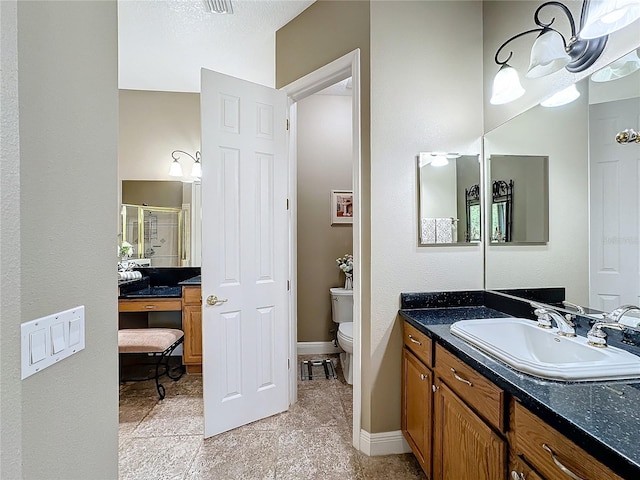 bathroom with a shower with door, vanity, and toilet