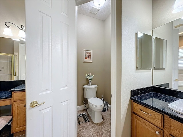 bathroom with vanity, toilet, and a shower with door