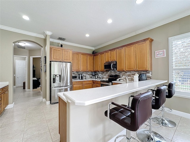 kitchen with decorative backsplash, kitchen peninsula, a breakfast bar area, and appliances with stainless steel finishes