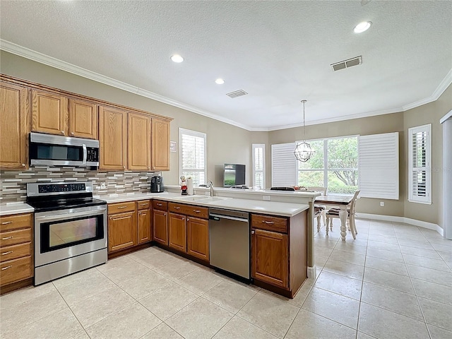 kitchen with sink, a notable chandelier, backsplash, light tile patterned floors, and appliances with stainless steel finishes