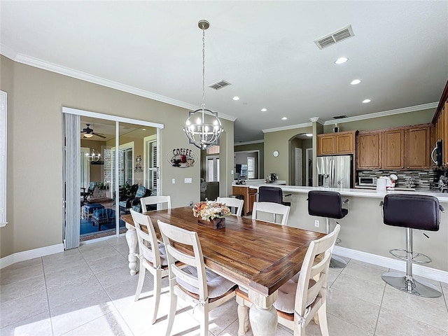 tiled dining room featuring ceiling fan with notable chandelier and crown molding