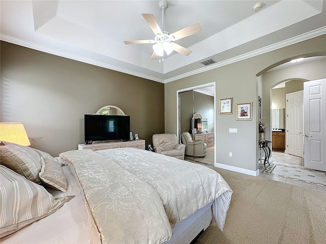 bedroom featuring ceiling fan, a raised ceiling, ornamental molding, and a closet