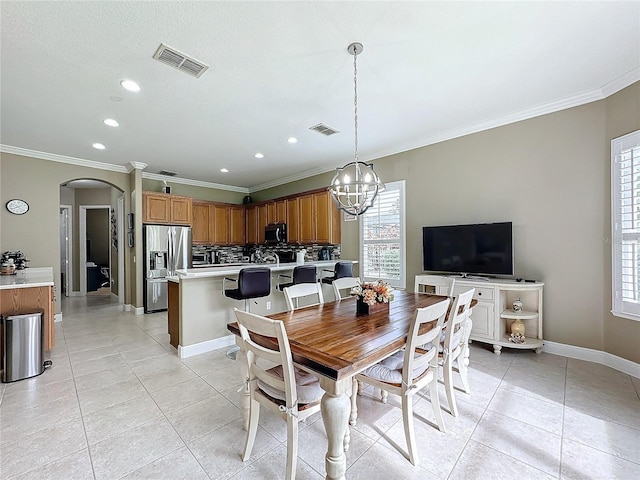 tiled dining room featuring ornamental molding and an inviting chandelier