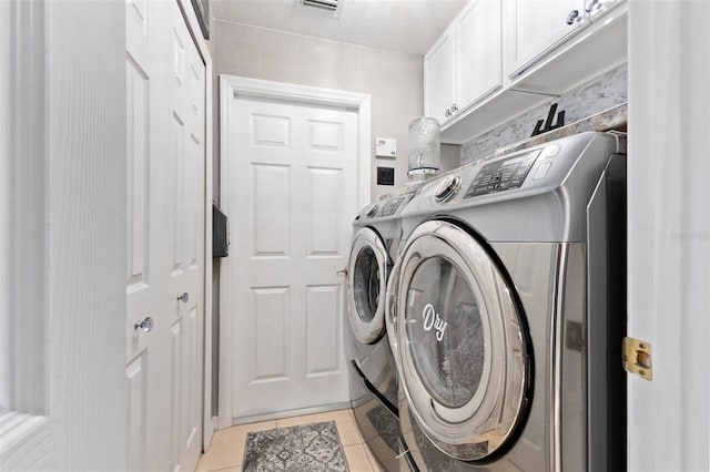 laundry area featuring cabinets, independent washer and dryer, a textured ceiling, and light tile patterned floors