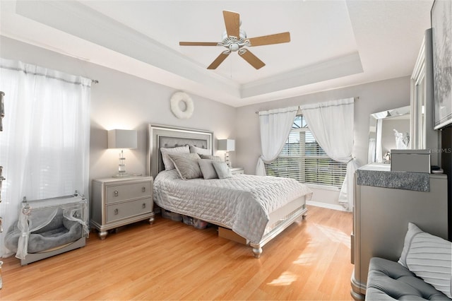 bedroom with a tray ceiling, ceiling fan, light hardwood / wood-style floors, and ornamental molding