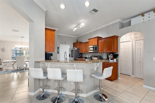 kitchen with kitchen peninsula, a breakfast bar, light tile patterned flooring, and appliances with stainless steel finishes