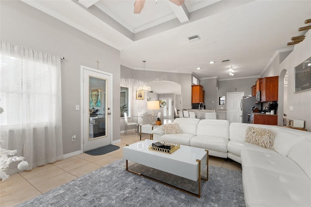 living room with ceiling fan, plenty of natural light, light tile patterned flooring, and ornamental molding