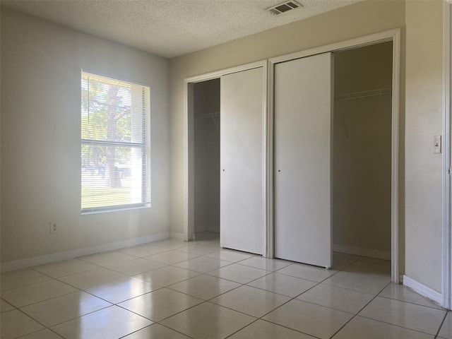 34 Pine Island Cir, Kissimmee, FL 34743 - unfurnished bedroom with multiple closets, a textured ceiling, and light tile patterned floors