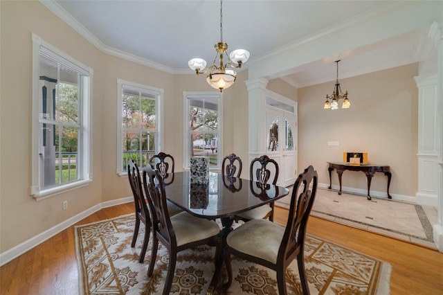 dining room featuring a chandelier, light hardwood / wood-style floors, decorative columns, and crown molding