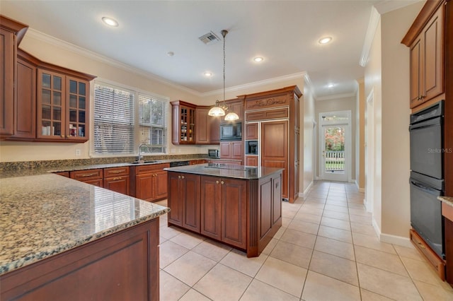 kitchen featuring a center island, dark stone counters, sink, hanging light fixtures, and built in appliances