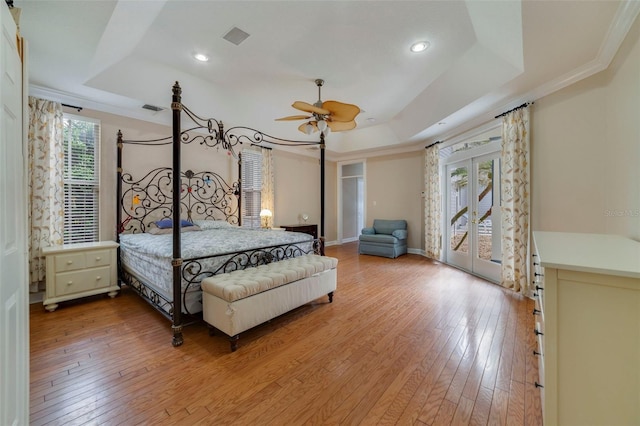 bedroom featuring ceiling fan, light hardwood / wood-style flooring, access to outside, and a tray ceiling