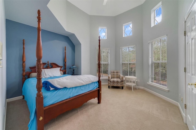 bedroom featuring ceiling fan, a towering ceiling, and light carpet