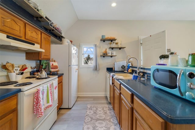 kitchen featuring white appliances, light hardwood / wood-style flooring, vaulted ceiling, and sink