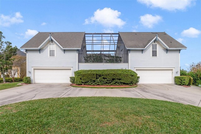 view of front of home with glass enclosure, a garage, and a front lawn