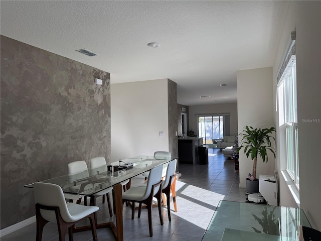 dining area featuring a textured ceiling and dark tile patterned flooring