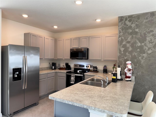 kitchen featuring a kitchen breakfast bar, sink, gray cabinets, appliances with stainless steel finishes, and kitchen peninsula