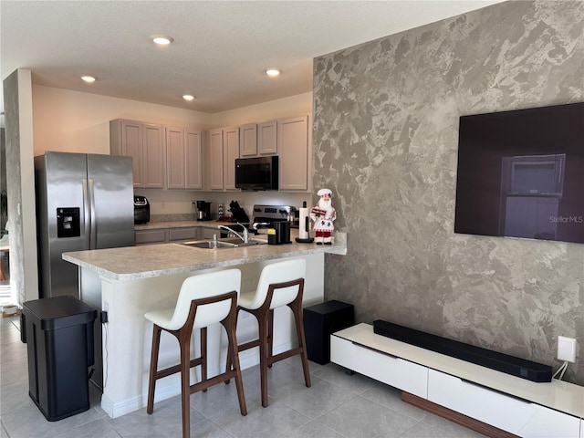 kitchen with kitchen peninsula, gray cabinetry, stainless steel appliances, sink, and a breakfast bar area