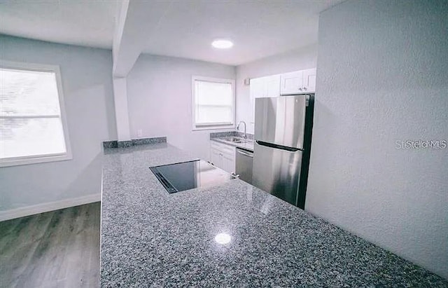 kitchen featuring dark stone countertops, white cabinetry, stainless steel appliances, and a wealth of natural light