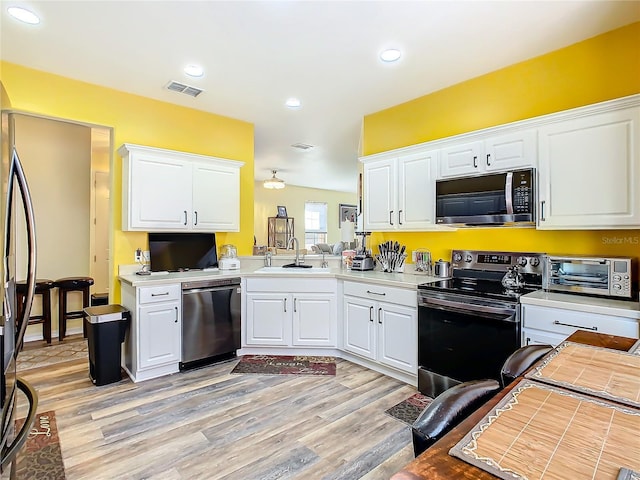 kitchen with white cabinetry, sink, light hardwood / wood-style flooring, and appliances with stainless steel finishes