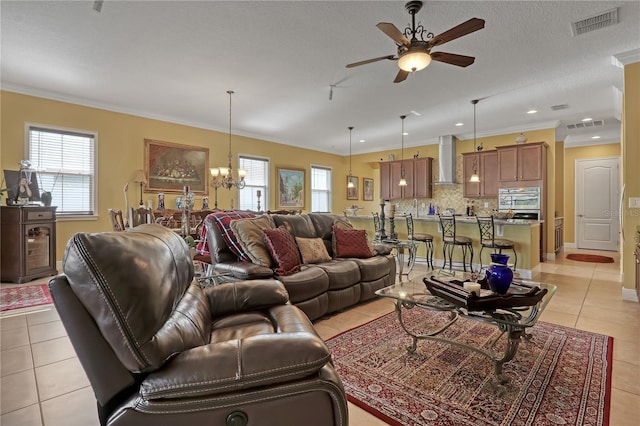 tiled living room with ceiling fan with notable chandelier, ornamental molding, and a textured ceiling