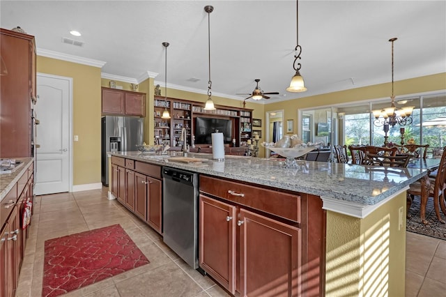 kitchen featuring light stone countertops, stainless steel appliances, an island with sink, decorative light fixtures, and ceiling fan with notable chandelier