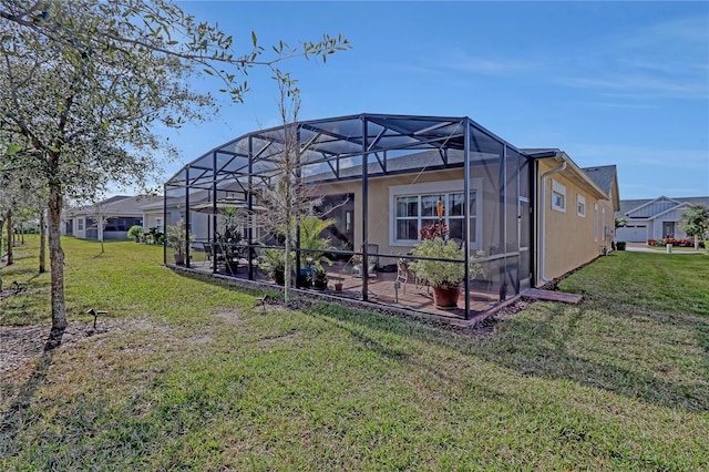 back of house with glass enclosure, a yard, and a patio