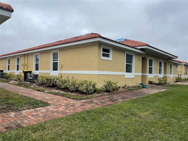 view of property exterior with a yard and central AC