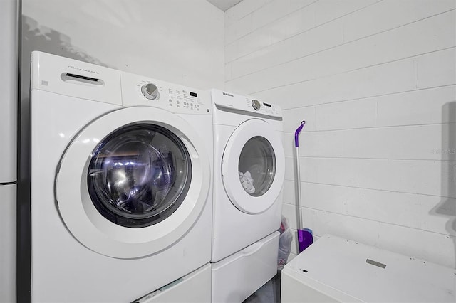 clothes washing area with separate washer and dryer and wood walls