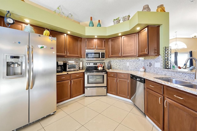 kitchen with sink, light stone countertops, light tile patterned floors, a notable chandelier, and stainless steel appliances