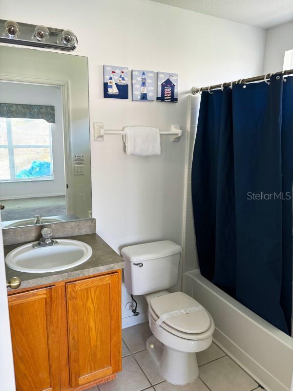 full bathroom with tile patterned flooring, vanity, toilet, and shower / bath combo with shower curtain