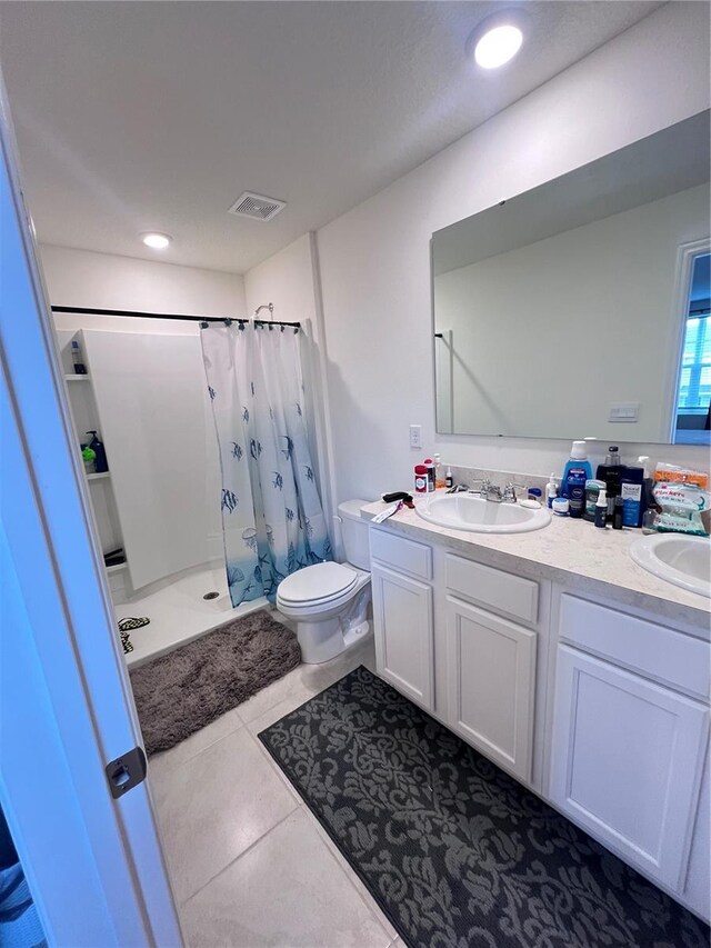 bathroom featuring tile patterned flooring, vanity, toilet, and curtained shower