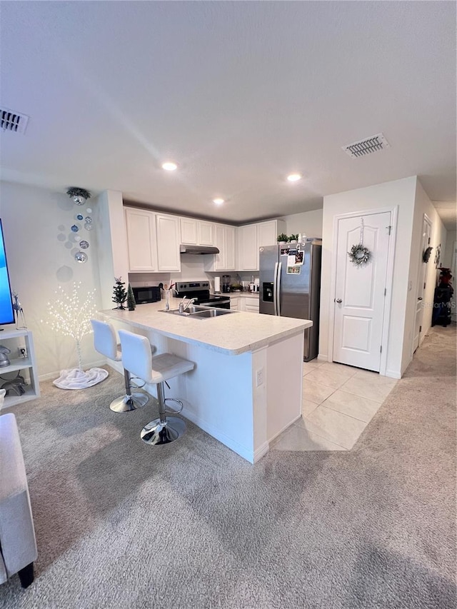 kitchen featuring kitchen peninsula, appliances with stainless steel finishes, a kitchen breakfast bar, light colored carpet, and white cabinets