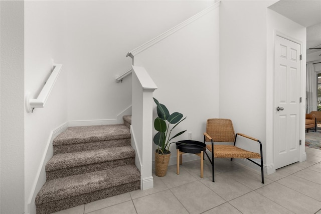 staircase featuring tile patterned floors and crown molding