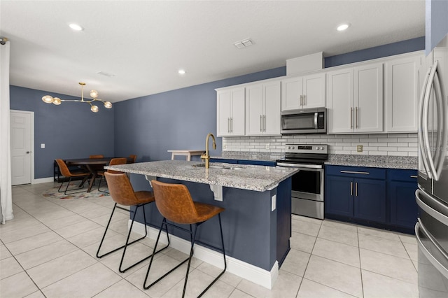 kitchen featuring decorative backsplash, appliances with stainless steel finishes, sink, a center island with sink, and white cabinets