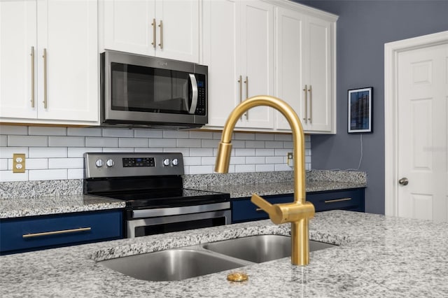 kitchen with decorative backsplash, white cabinetry, light stone countertops, and appliances with stainless steel finishes