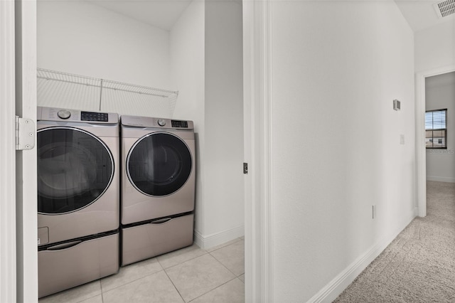 laundry room featuring washing machine and clothes dryer and light tile patterned floors