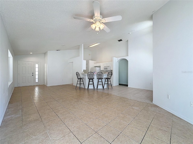 interior space with a textured ceiling, high vaulted ceiling, and ceiling fan